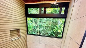 Une douche avec une fenêtre, un plafond en bois et des murs carrelés.