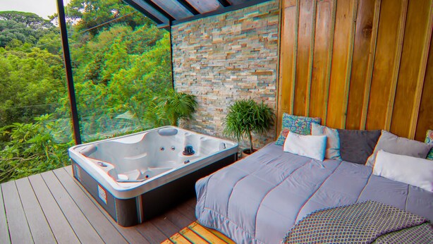 Une chambre dotée d’un grand lit, d’un jacuzzi et offrant une vue sur une végétation luxuriante.