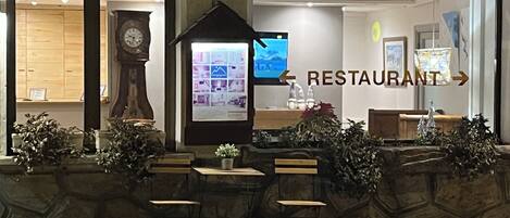 A restaurant with a stone facade, wooden tables, and a clock.