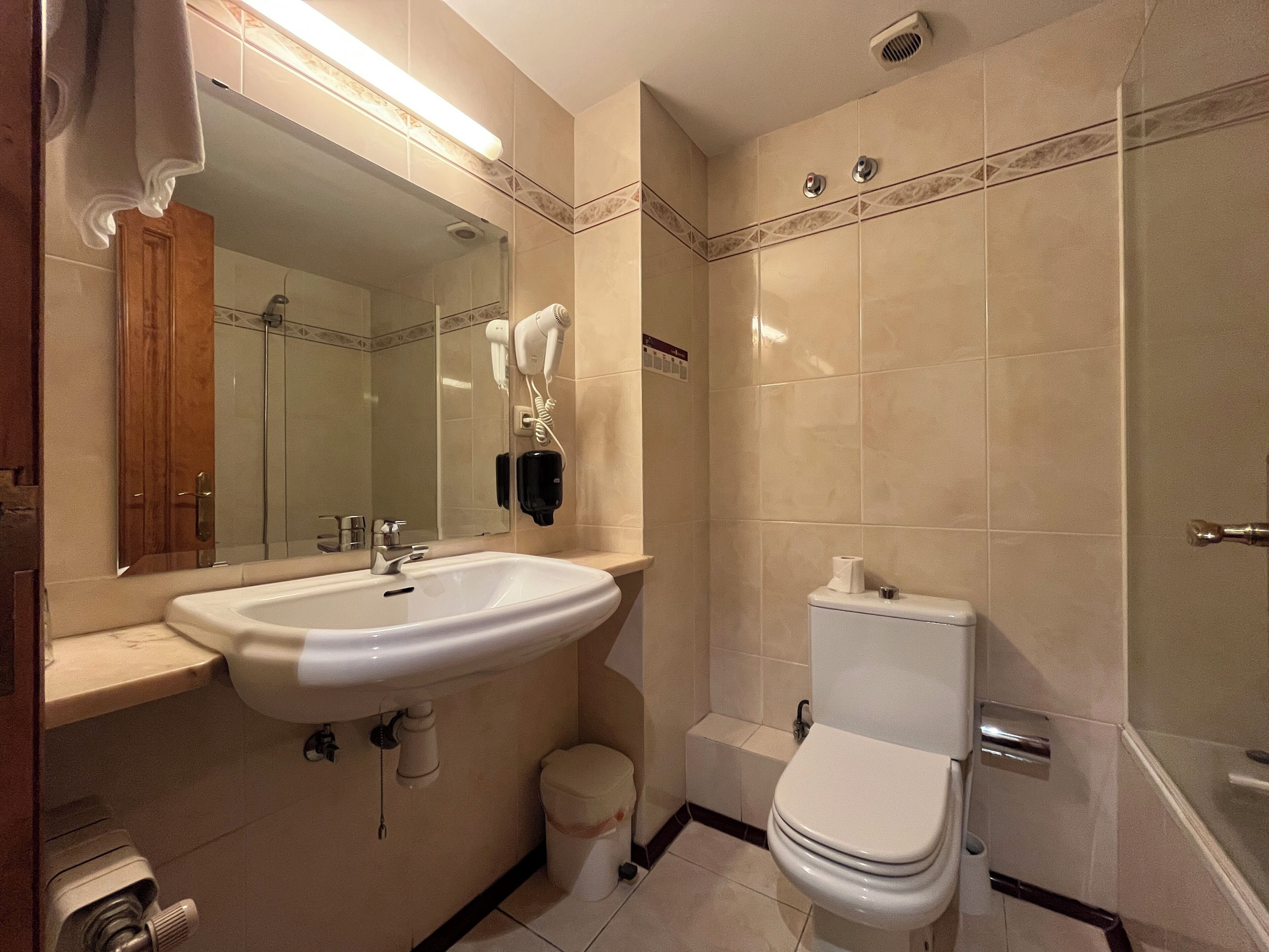A modern bathroom with a large sink, mirror, and toilet.