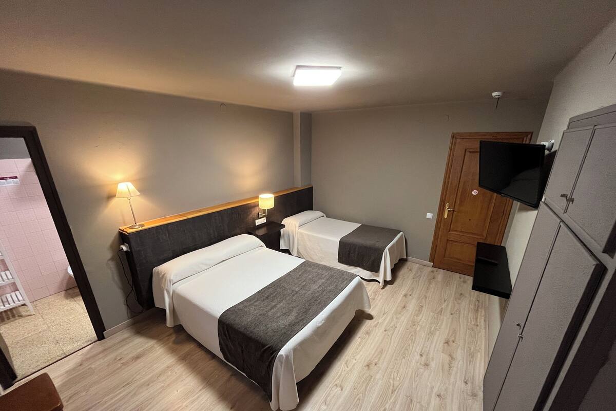 A hotel room with two beds, a TV, and a wardrobe.