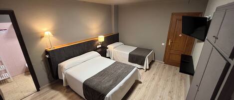 Habitación de hotel con dos camas, televisión y armario.