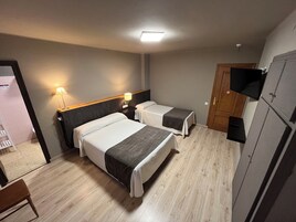 A hotel room with two beds, a TV, and a wardrobe.