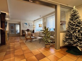 A living room with a large Christmas tree, a fireplace, and a sofa.