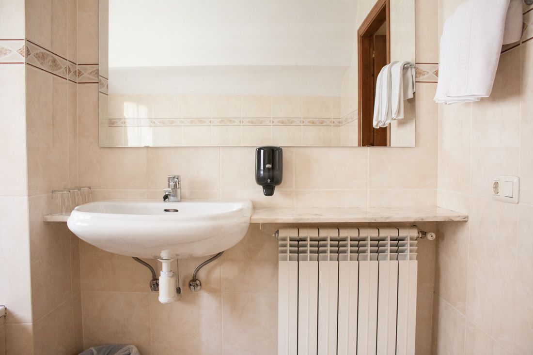 A bathroom with a white sink, a mirror, and a towel rack.