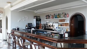A bar area with a marble countertop, bar stools, a coffee machine, and shelves stocked with bottles and snacks. - Hotel Santa Fe (Santa Fe)