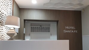 A hotel reception area with a modern design, including a reception desk, a decorative wall, and a sign that reads "HOTEL SANTA FE". - Hotel Santa Fe (Santa Fe)