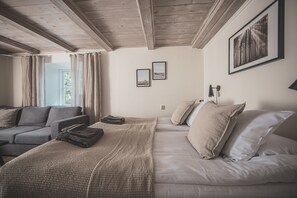 A bedroom with a bed, a sofa, and a window. There are two framed pictures on the wall. - Gumbalde Resort (Stånga)
