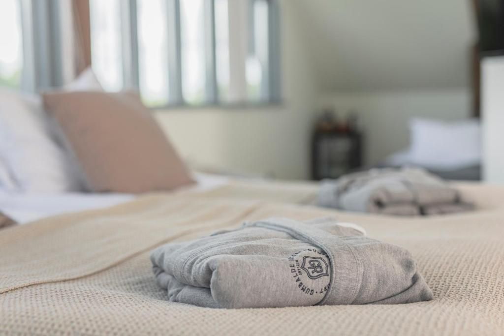 A neatly made bed with a folded blanket and a pillow with a logo.