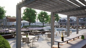 Een terras buiten met tafels en stoelen, een zwembad en een pergola.