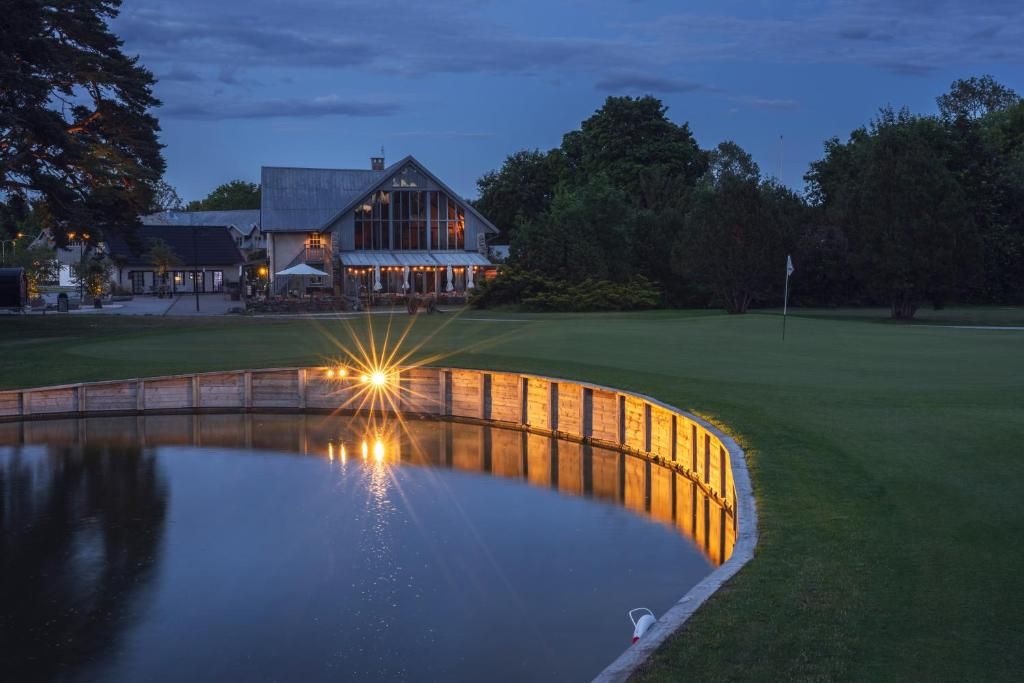 A large building with a reflective water feature in front, surrounded by a well-maintained lawn.