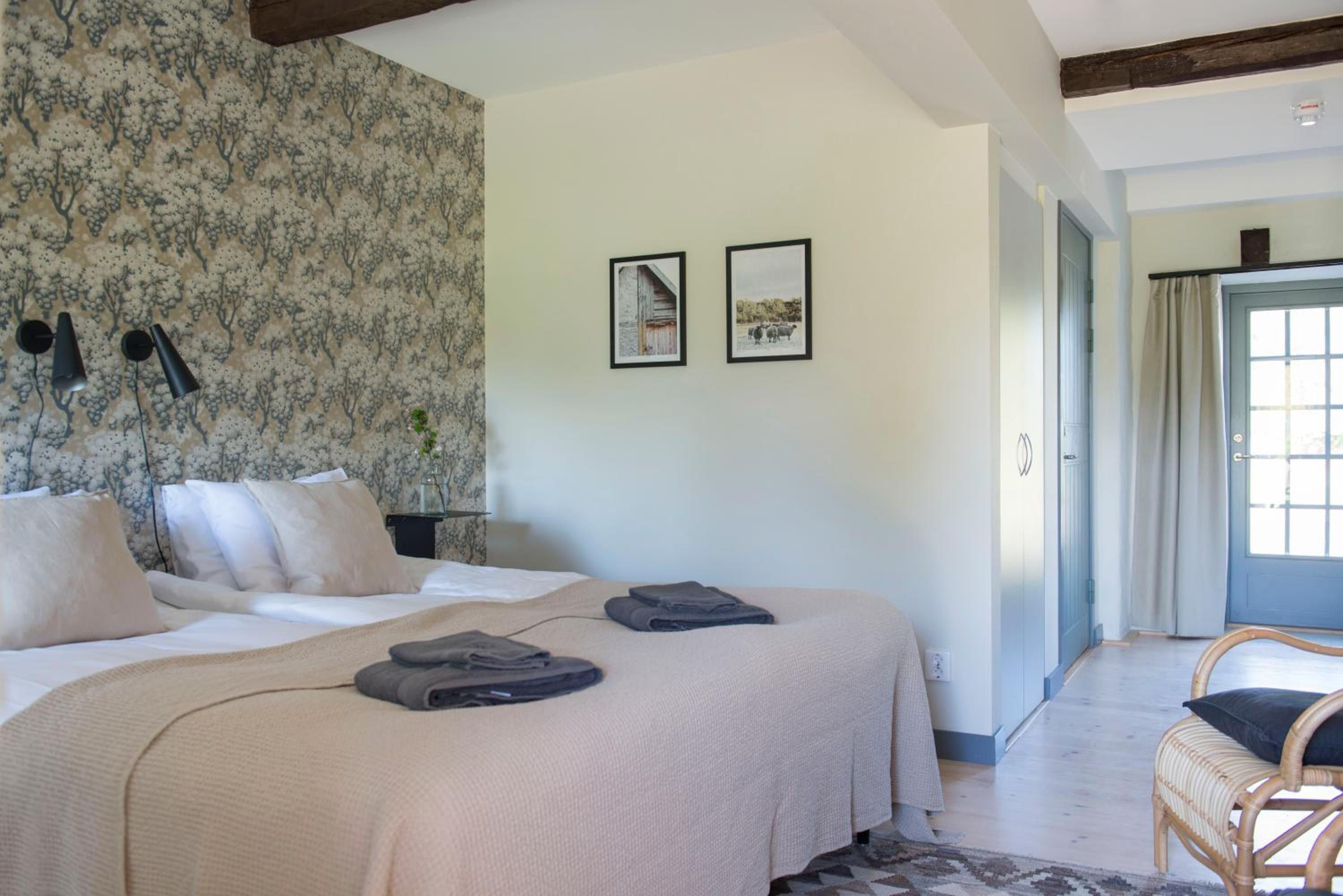A bedroom with a bed, two framed pictures, a nightstand, and a chair.
