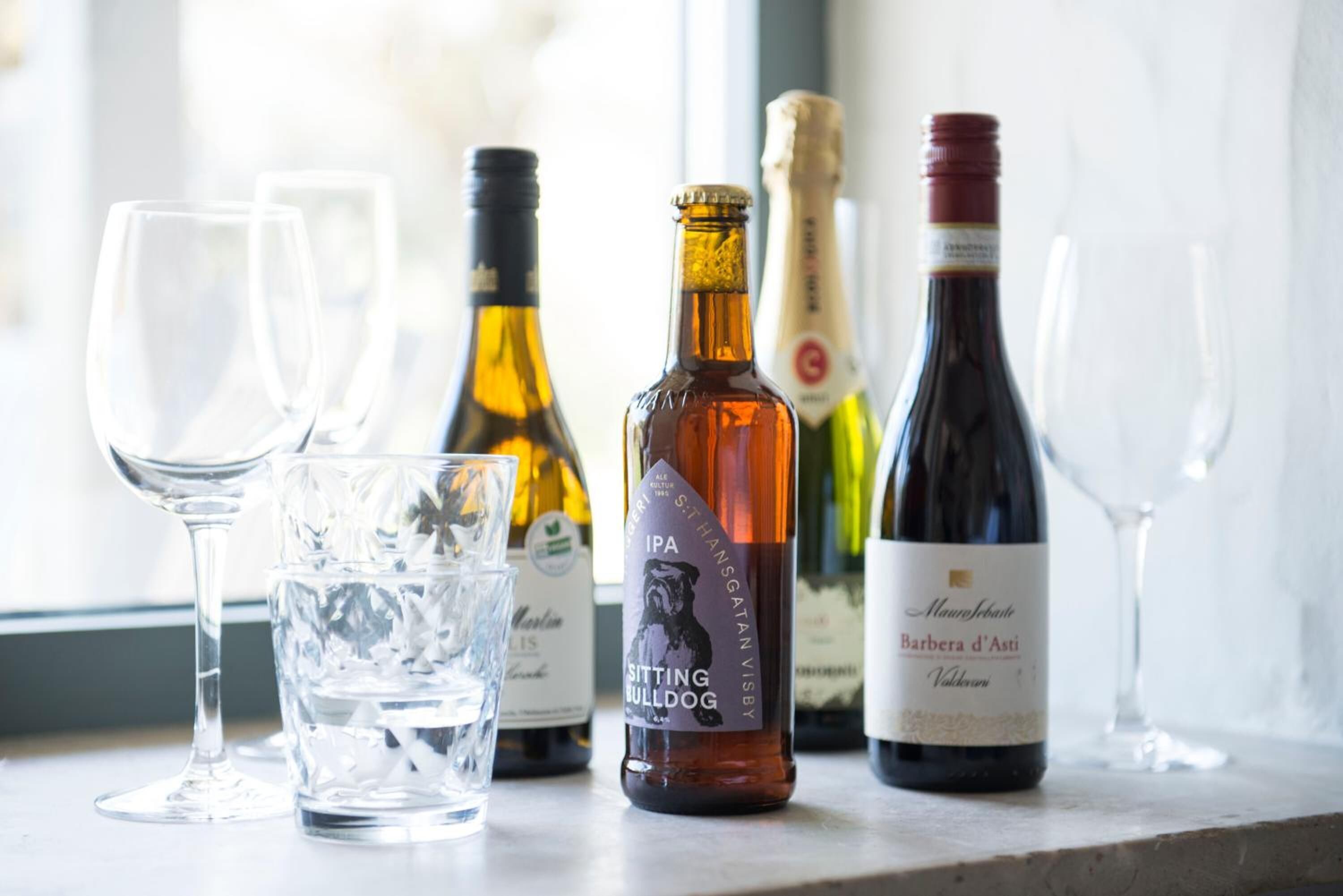 A selection of wine bottles and glasses on a table by a window.