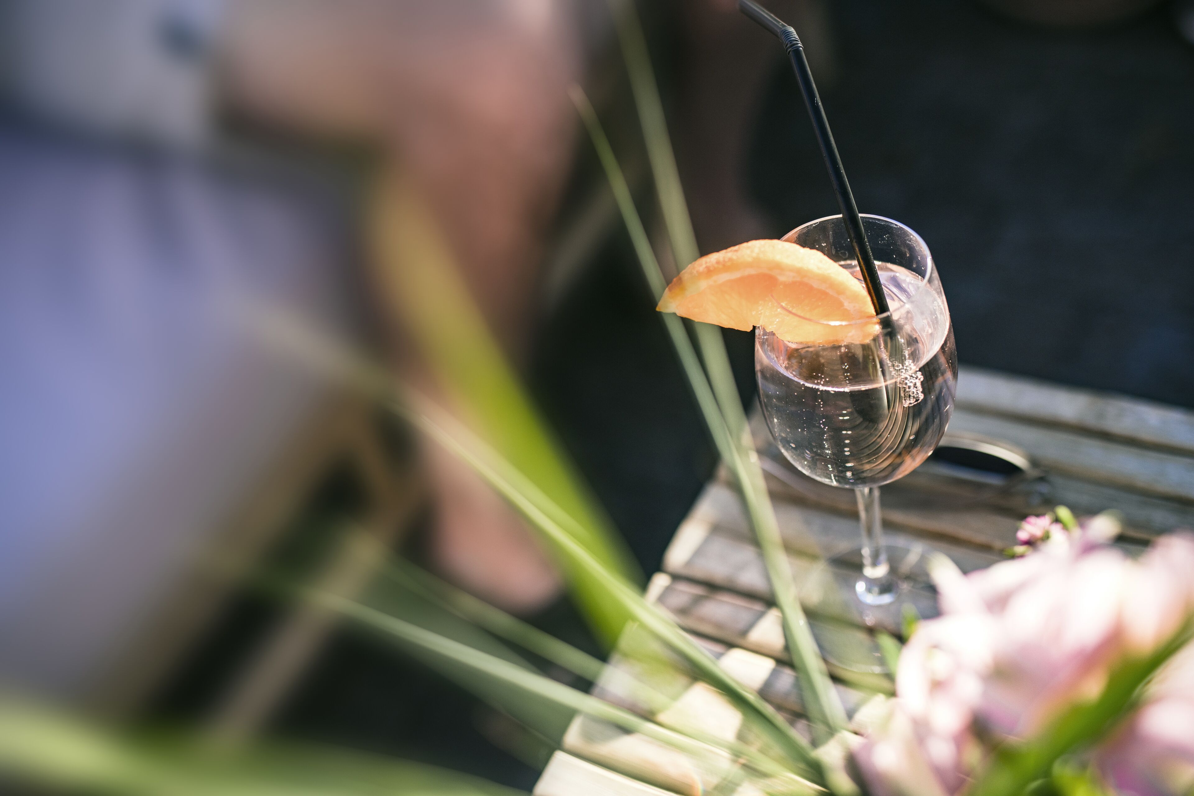 A glass with a straw and a slice of orange on a table.