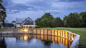 Hotel aan een meer met een houten terras en een spiegelbeeld in het water.