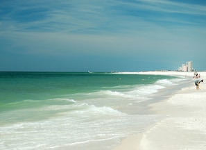 A beach with clear turquoise water, white sand, and a few people.