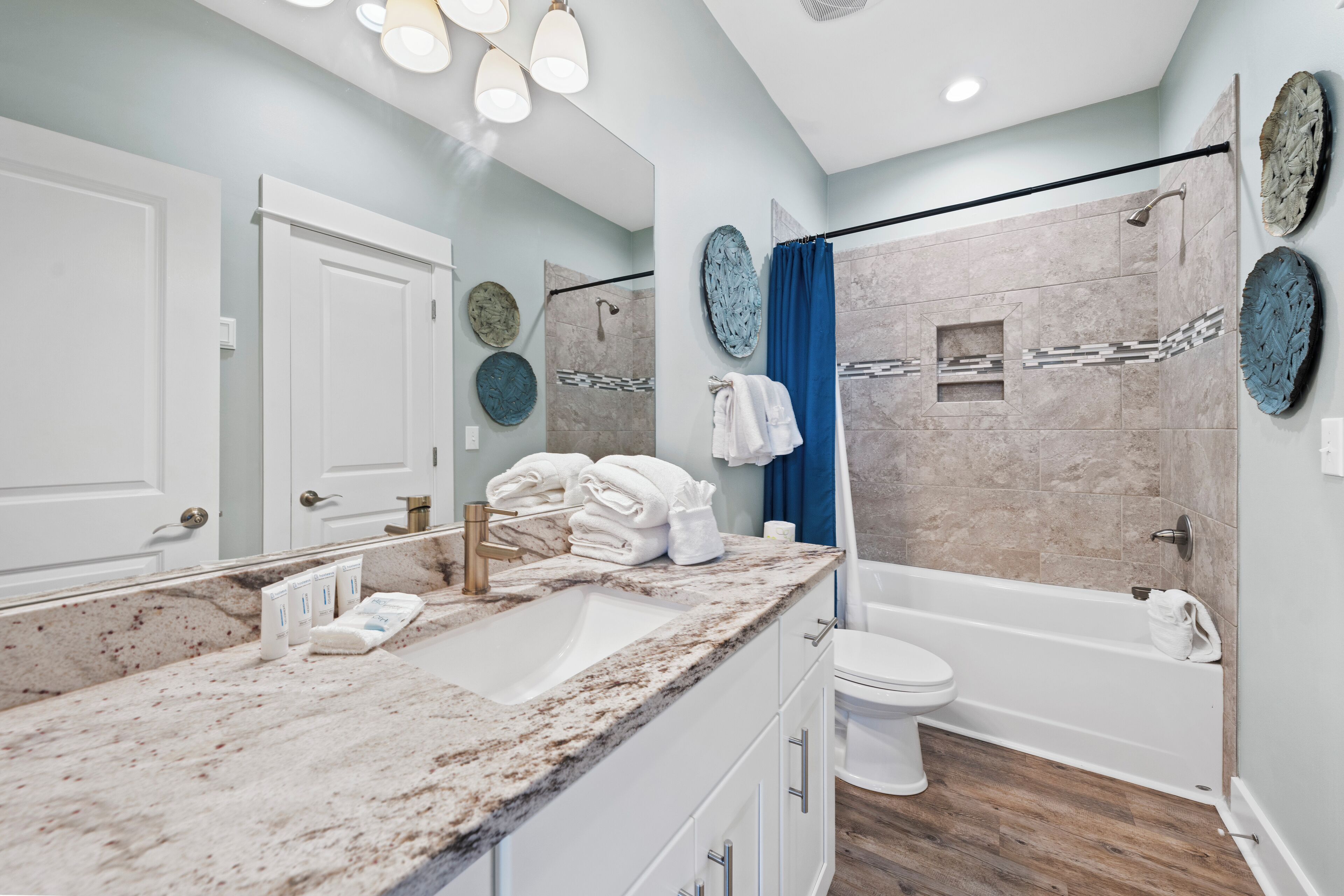 A modern bathroom with a marble sink, a toilet, and a bathtub.