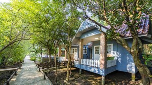 Una casa con fachada azul, cimientos de ladrillo y una cerca de piquetes blancos.