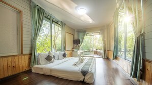 Un dormitorio espacioso con una cama grande, pisos de madera y ventanas amplias con cortinas.