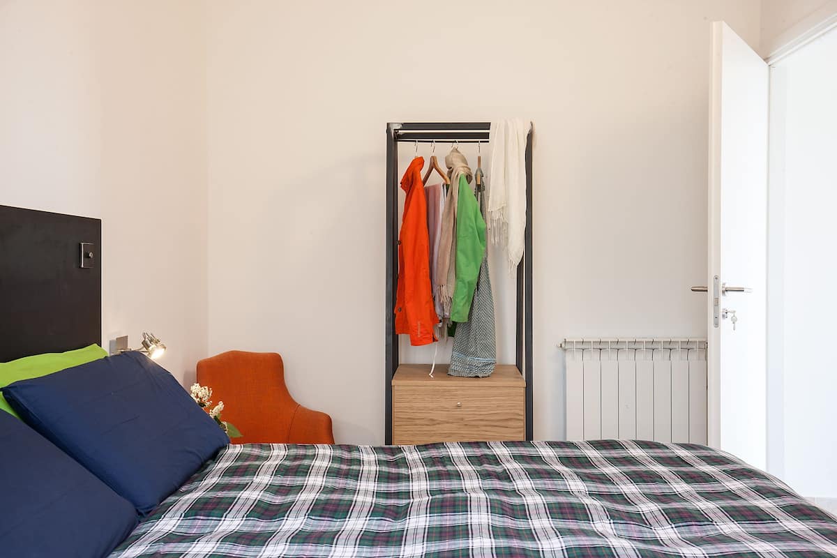 Ein Schlafzimmer mit Bett, Sessel, Kleiderschrank und Heizkörper.