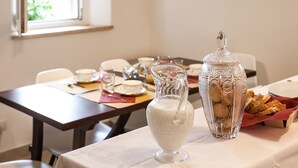 Une table à manger dressée avec de la vaisselle transparente, un pichet et un bocal muni d’un couvercle.