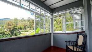 A room with a bay window overlooking a lush landscape, a wooden bench, and a red floor. - Mount Mary Inn (Nuwara Eliya)