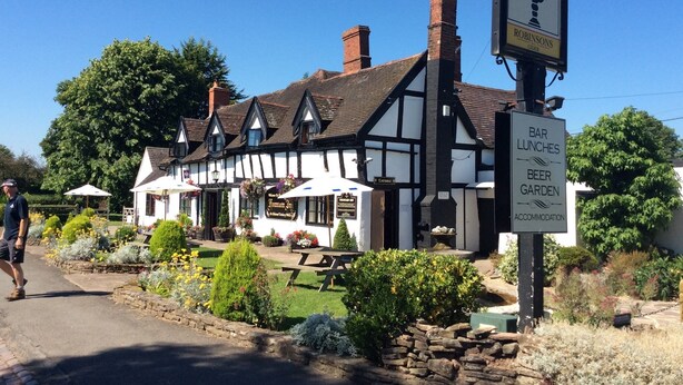 En traditionel bygning i Tudor-stil med skilt for 'Fountain Inn' og 'Robinsons'.