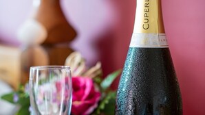 En flaske Cuperly champagne og to tomme glas på en træoverflade.