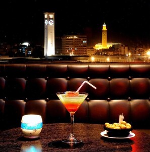 A cocktail on a table with a view of a cityscape in the background. - Hotel Washington (Casablanca)