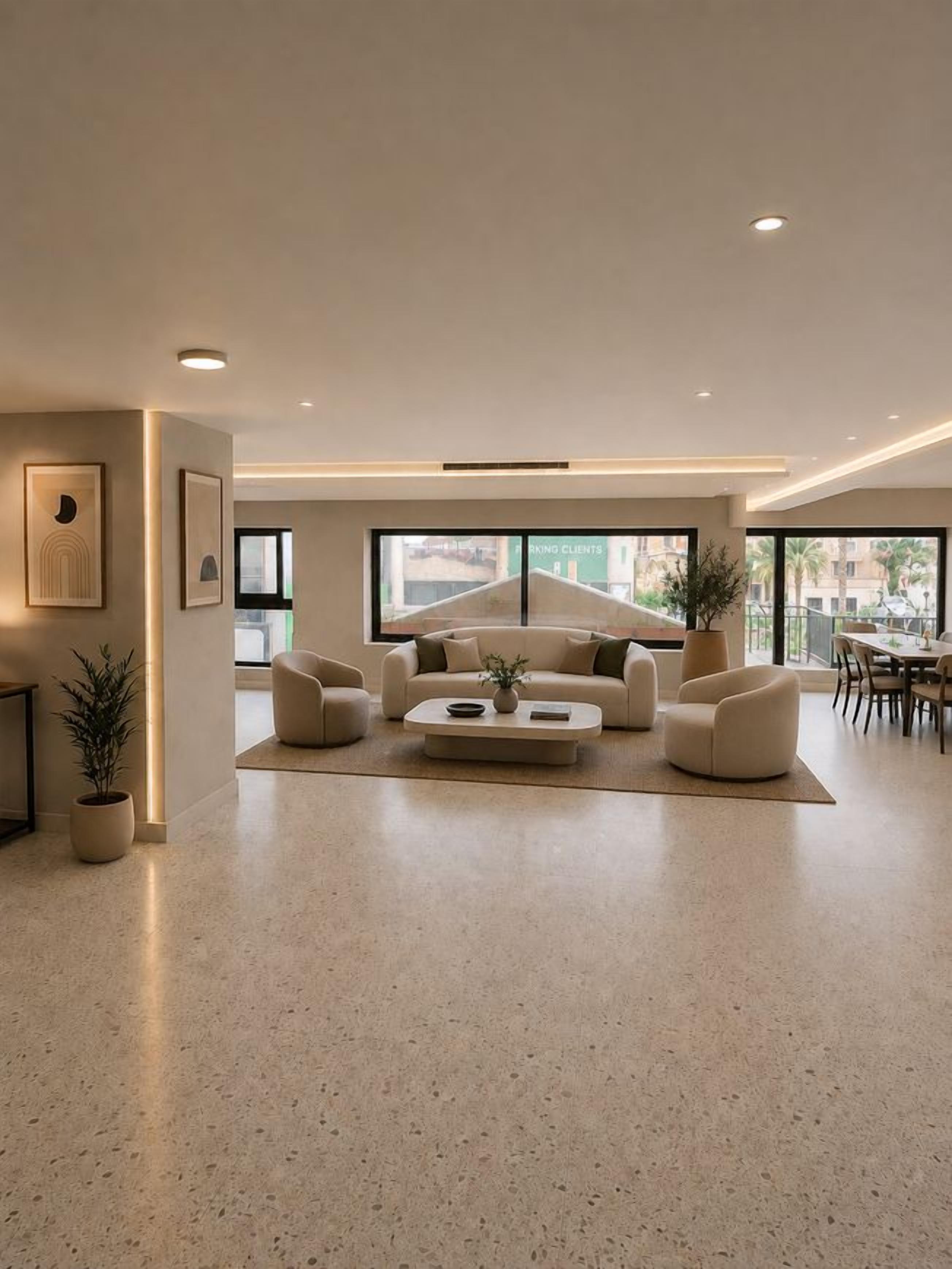 Un salon moderne avec une grande fenêtre, un ensemble de canapés, une table basse et un coin repas.
