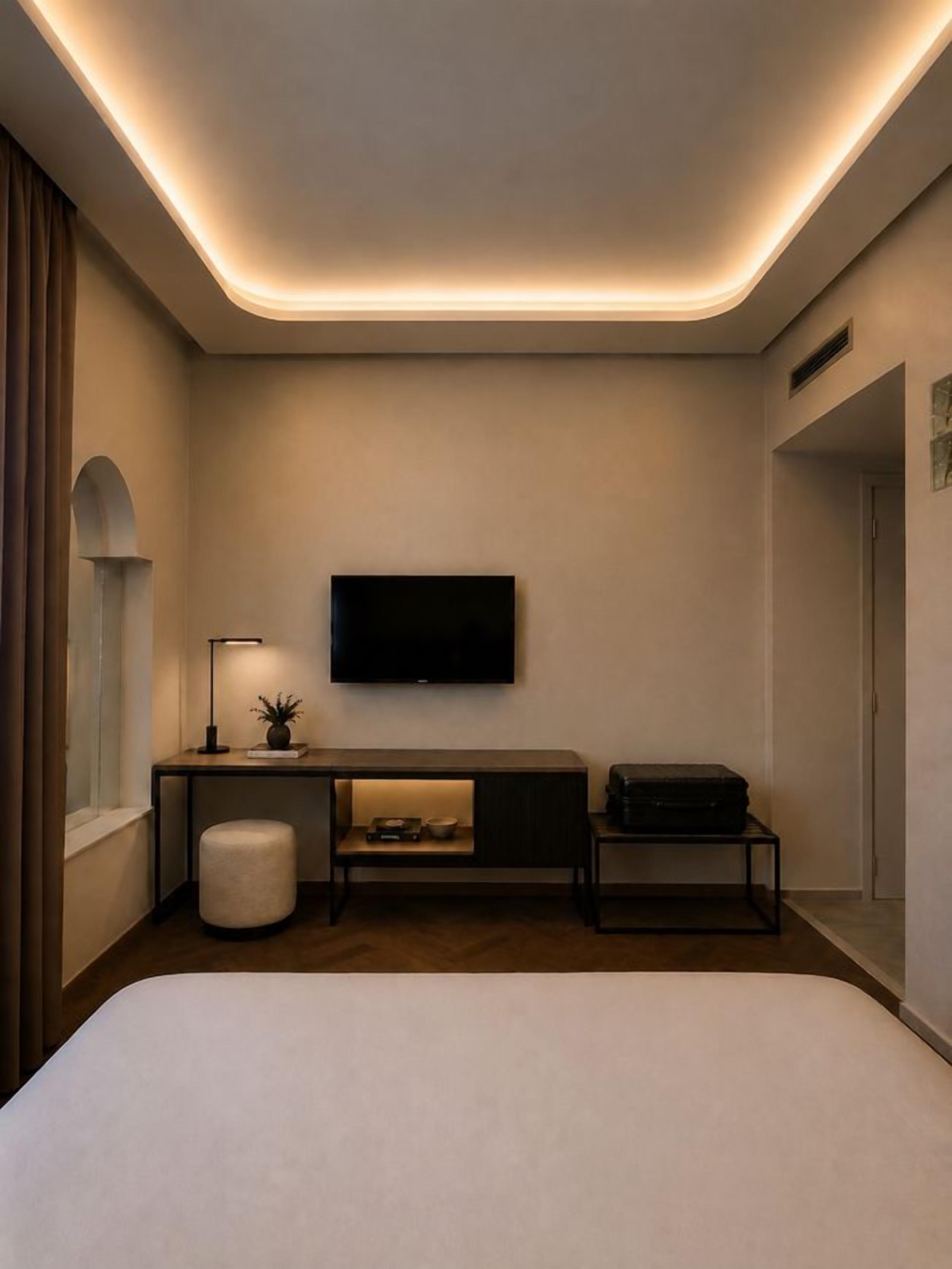 Une chambre d’hôtel moderne dotée d’un grand lit, d’un bureau avec un téléviseur à écran plat, d’une petite table et d’une chaise.