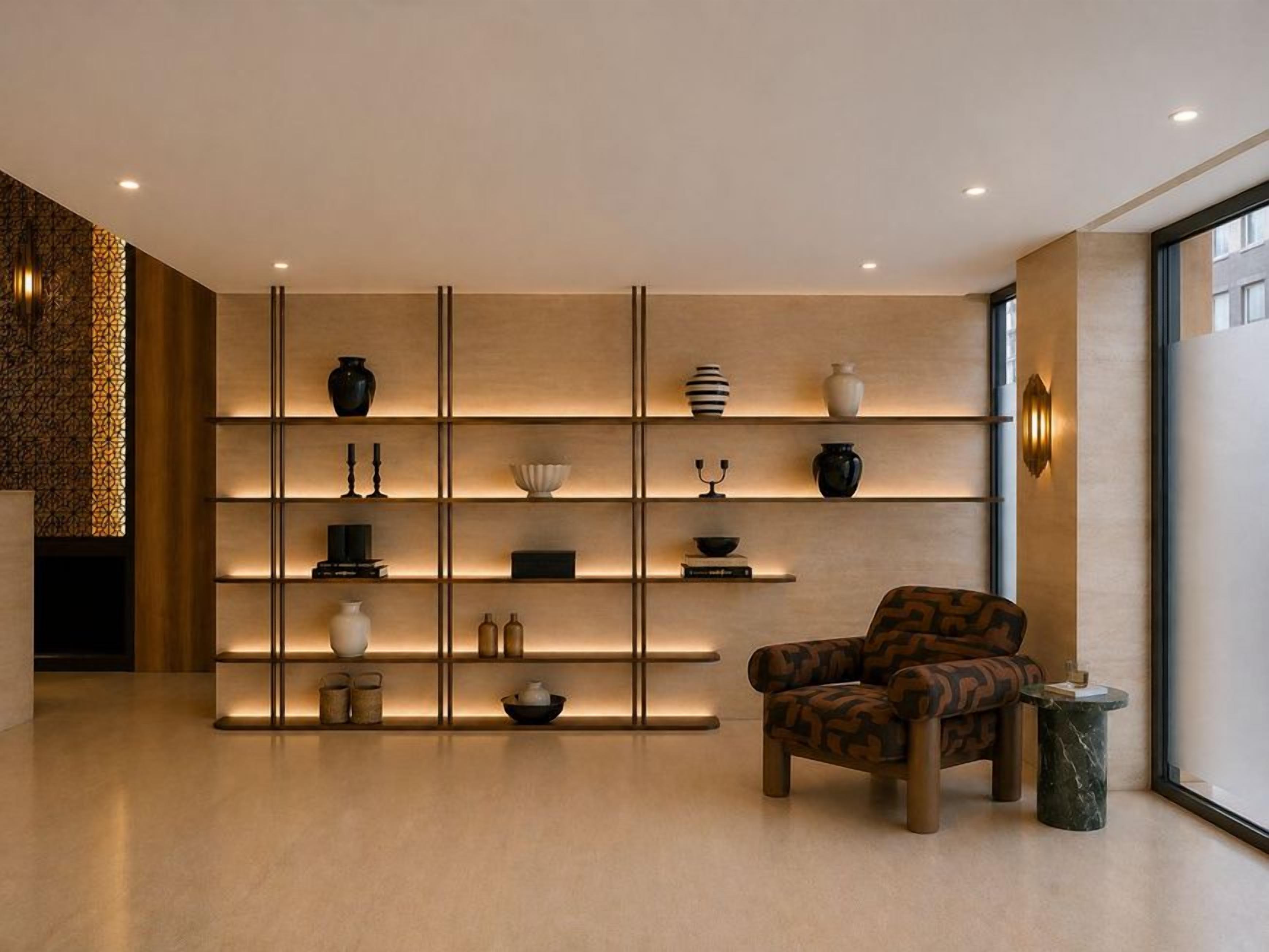 Un intérieur moderne avec un plancher en bois, un fauteuil à motifs et une étagère murale agrémentée d’objets décoratifs.