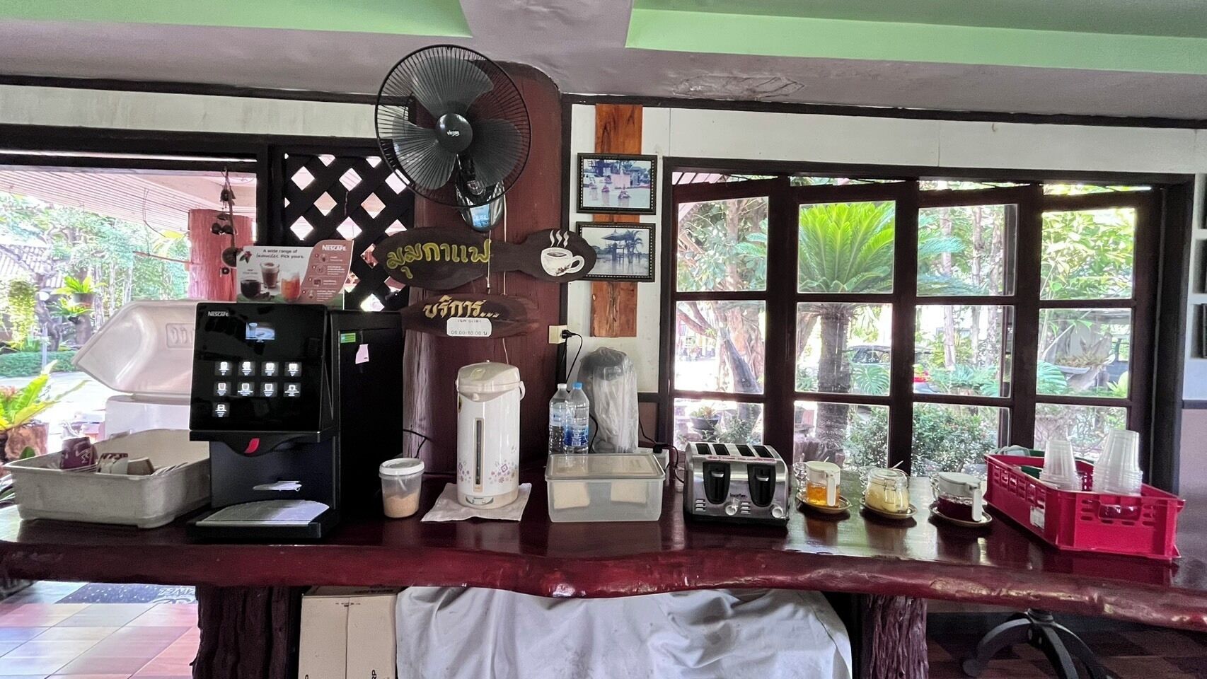 A coffee station with a coffee maker, grinder, and a fan.