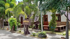 Un hotel con un cartel que dice "Hotel 1-6", rodeado de exuberante vegetación y un camino pavimentado.