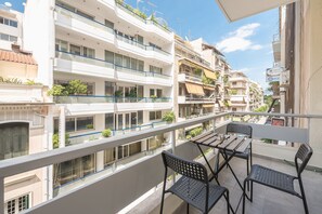 A balcony with a table and chairs, overlooking a residential area with multiple buildings. - Victoria Secret Apartments (Athens)