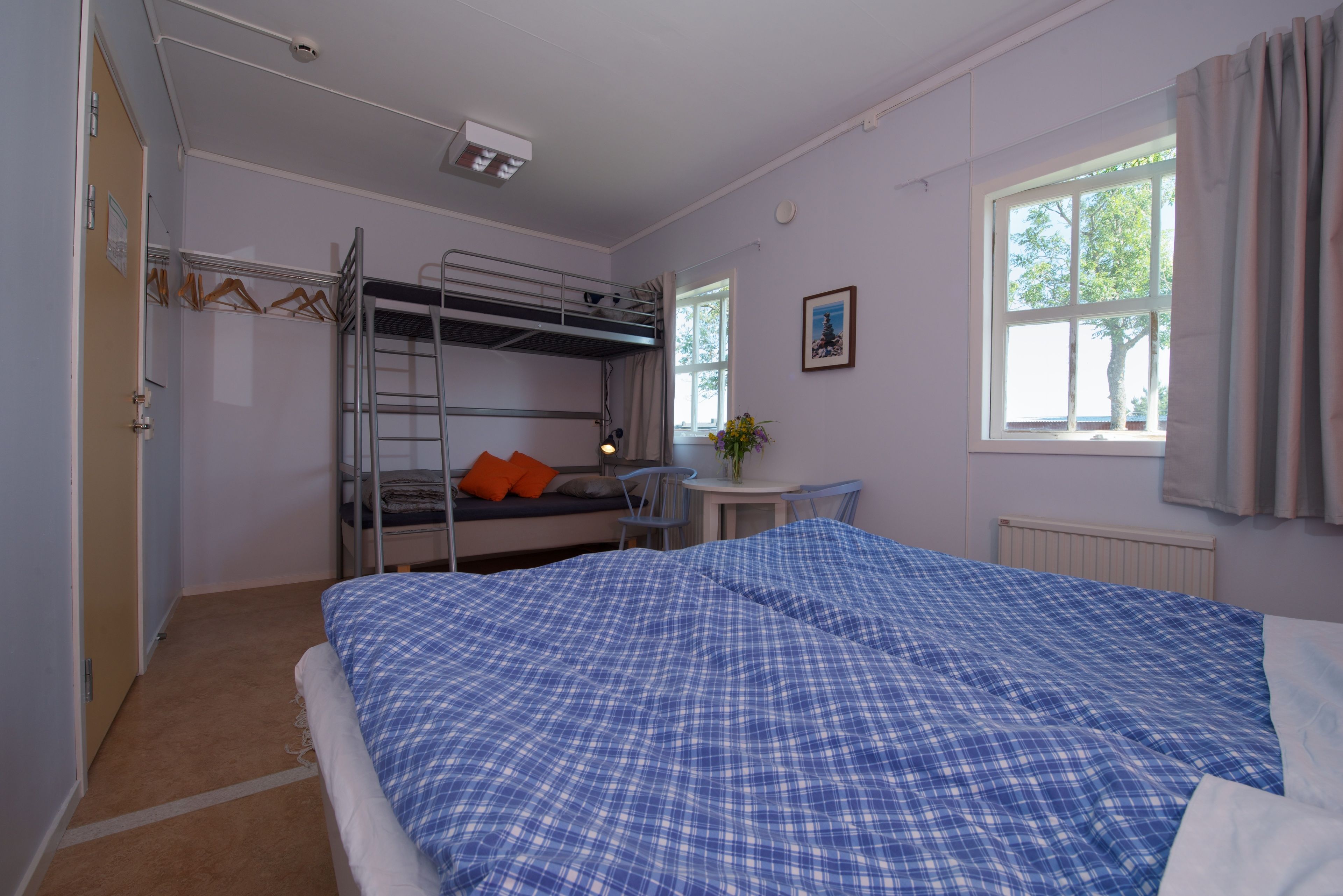 Una habitación con literas, un escritorio, una silla y una ventana con cortinas.