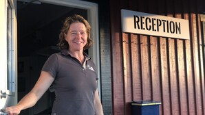 En person står vid en dörr med skylten ”RECEPTION” och en brevlåda sitter på väggen.