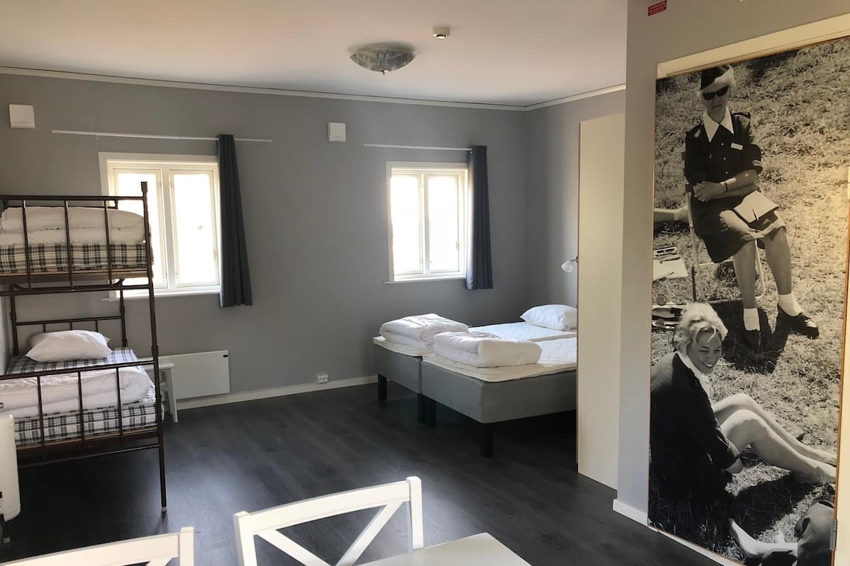 Ein Zimmer mit Etagenbetten, einem Einzelbett, einem Tisch und einem großen Schwarzweißfoto an der Wand.