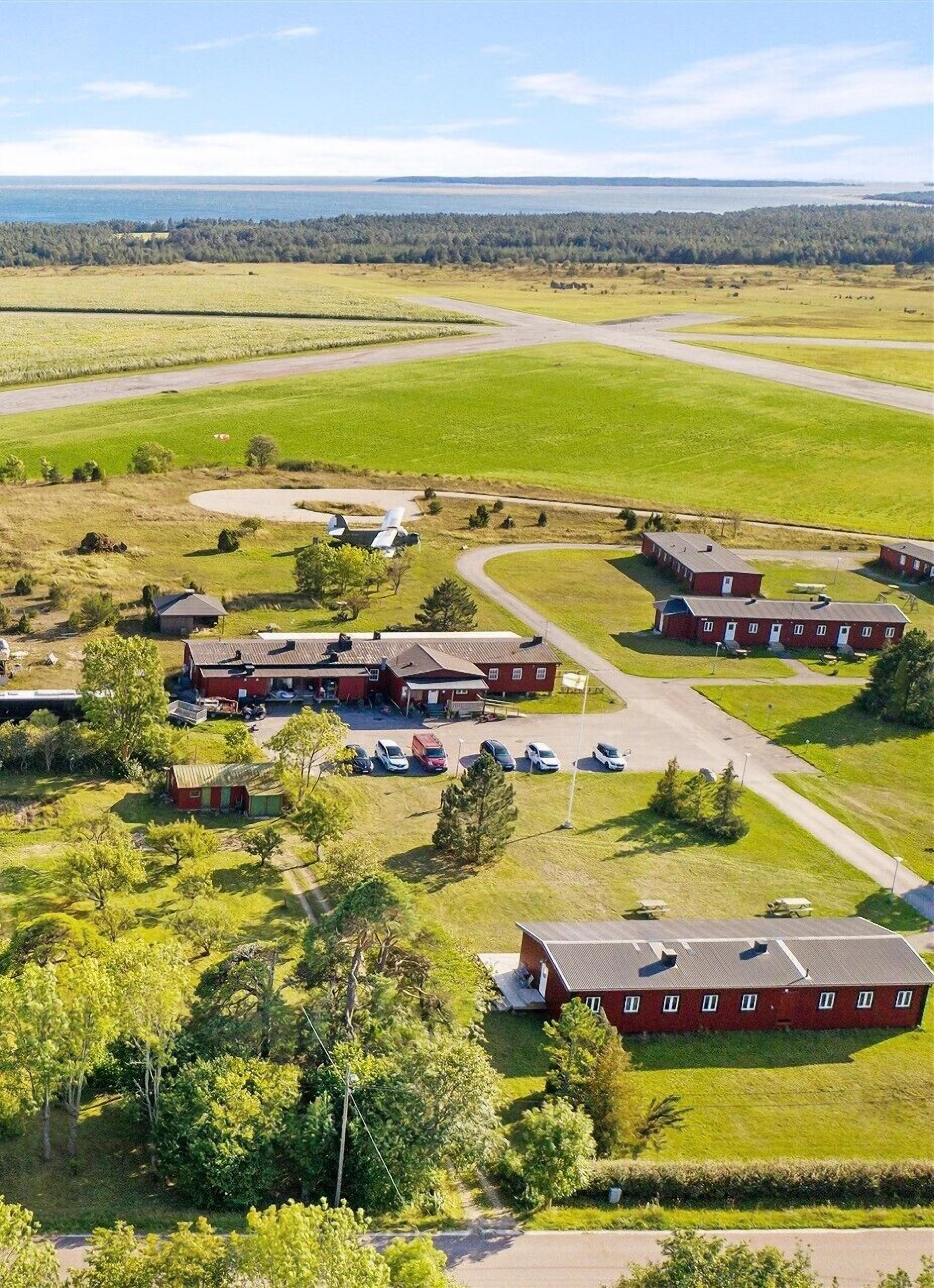 A large, open-air facility with multiple buildings, parking areas, and a surrounding green landscape.