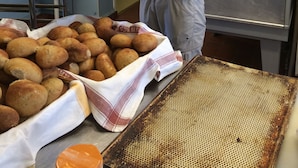 En person som håller ett bricka med bakverk i ett kök med rostfria köksredskap och ett metallställ.