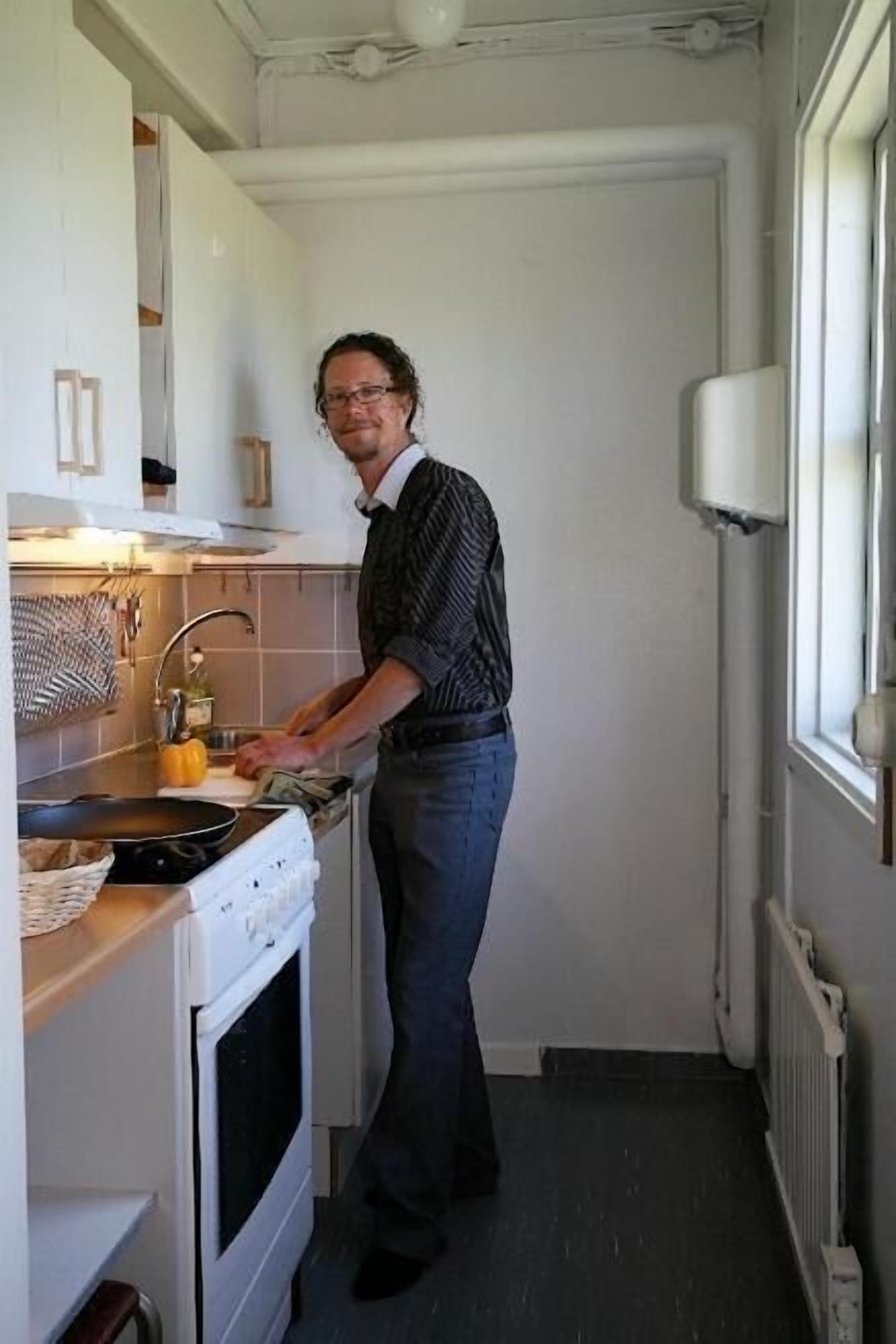 A narrow kitchen with a stove, sink, and window.
