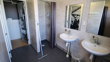 A bathroom with two sinks, a shower, and a mirror.