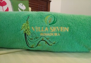Toalha verde com bordado de texto e um desenho de folha.