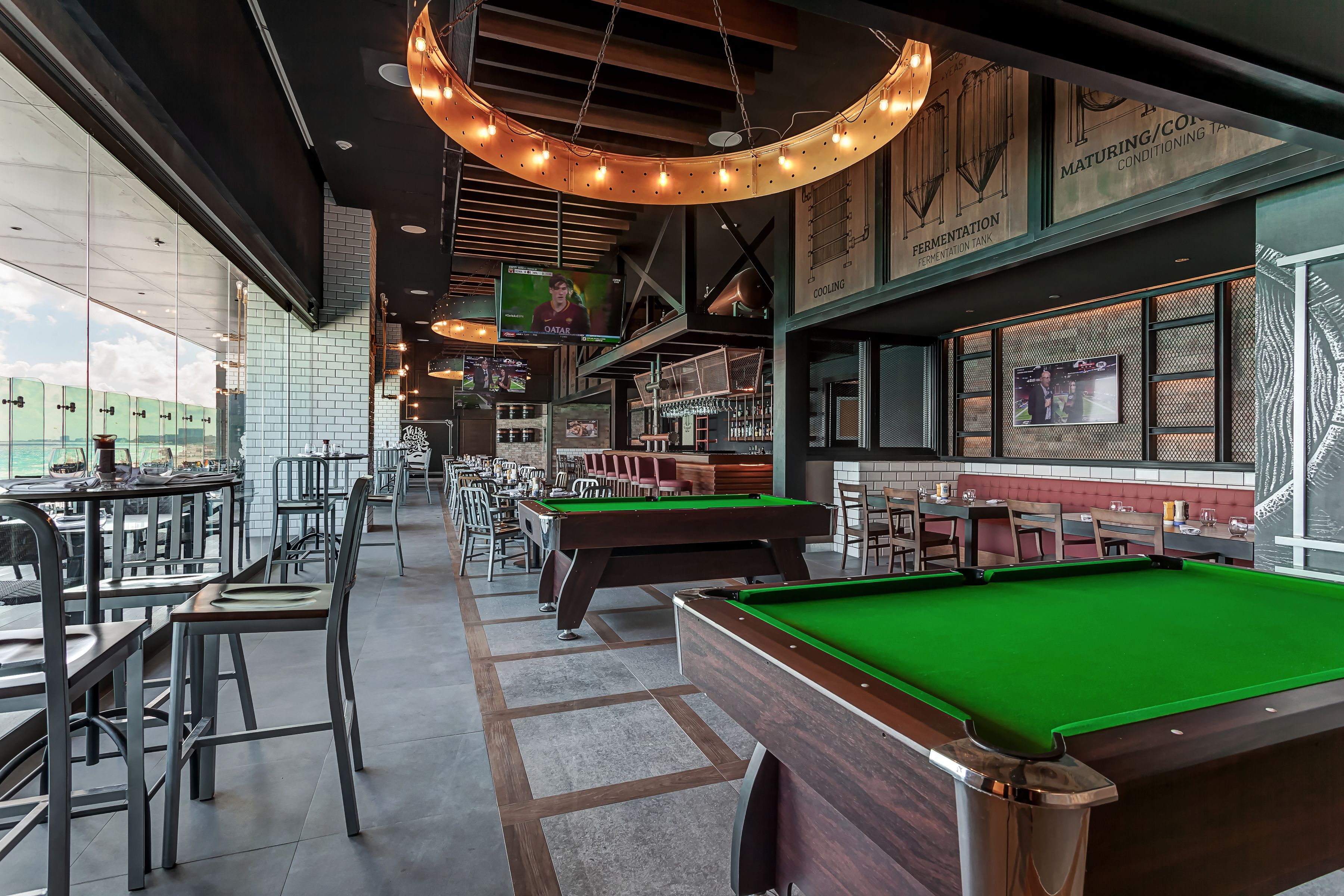 A billiards room with tables and chairs, a pool table, and a bar area with seating.