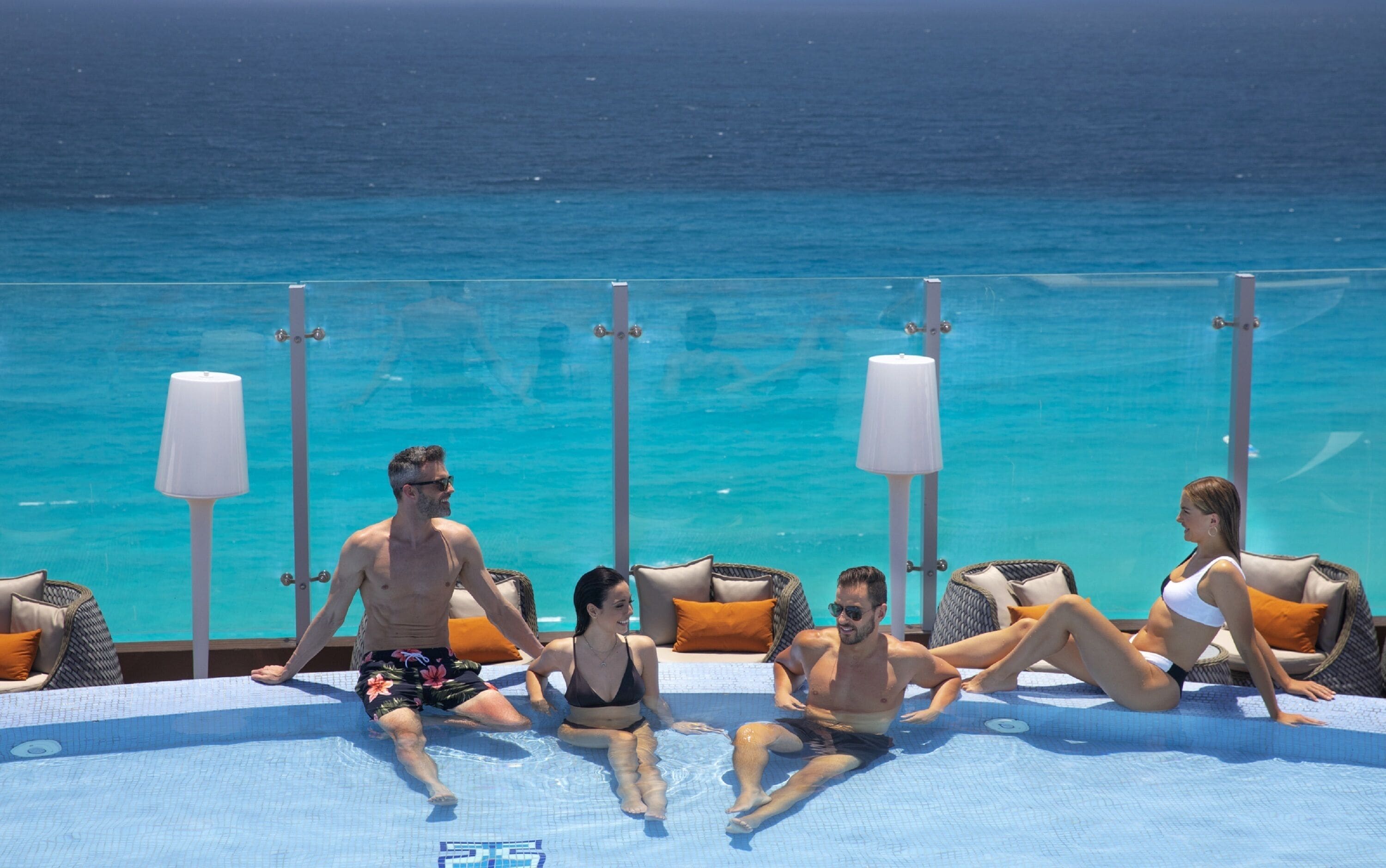 A poolside area with lounge chairs and a view of the ocean.