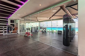 A gym with exercise equipment and a punching bag, overlooking a scenic ocean view.