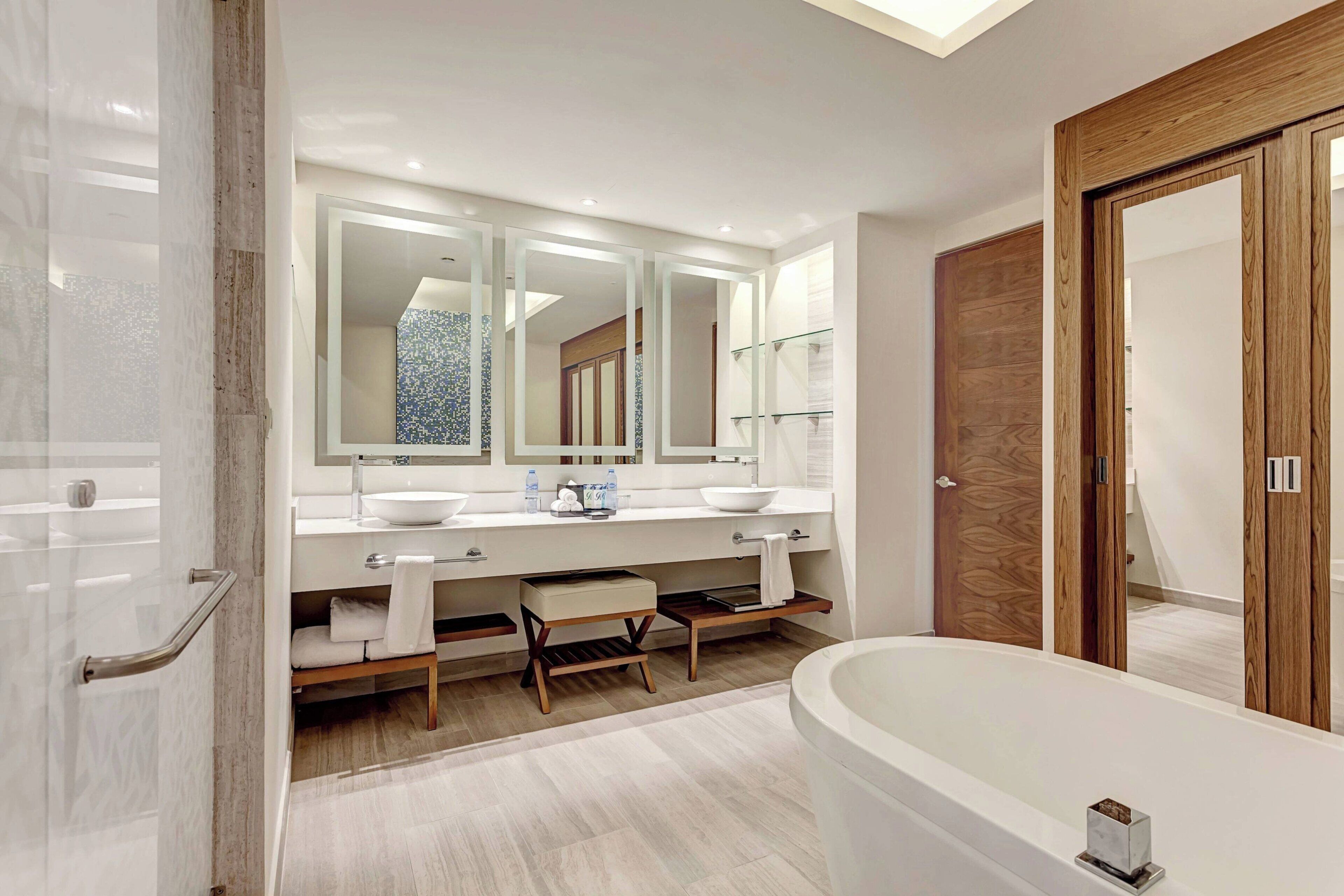 Une salle de bain moderne avec une grande baignoire, un meuble-lavabo à deux vasques et une porte en bois.