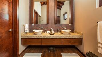 A bathroom with two sinks, wooden vanity, large mirror, and a wooden door.