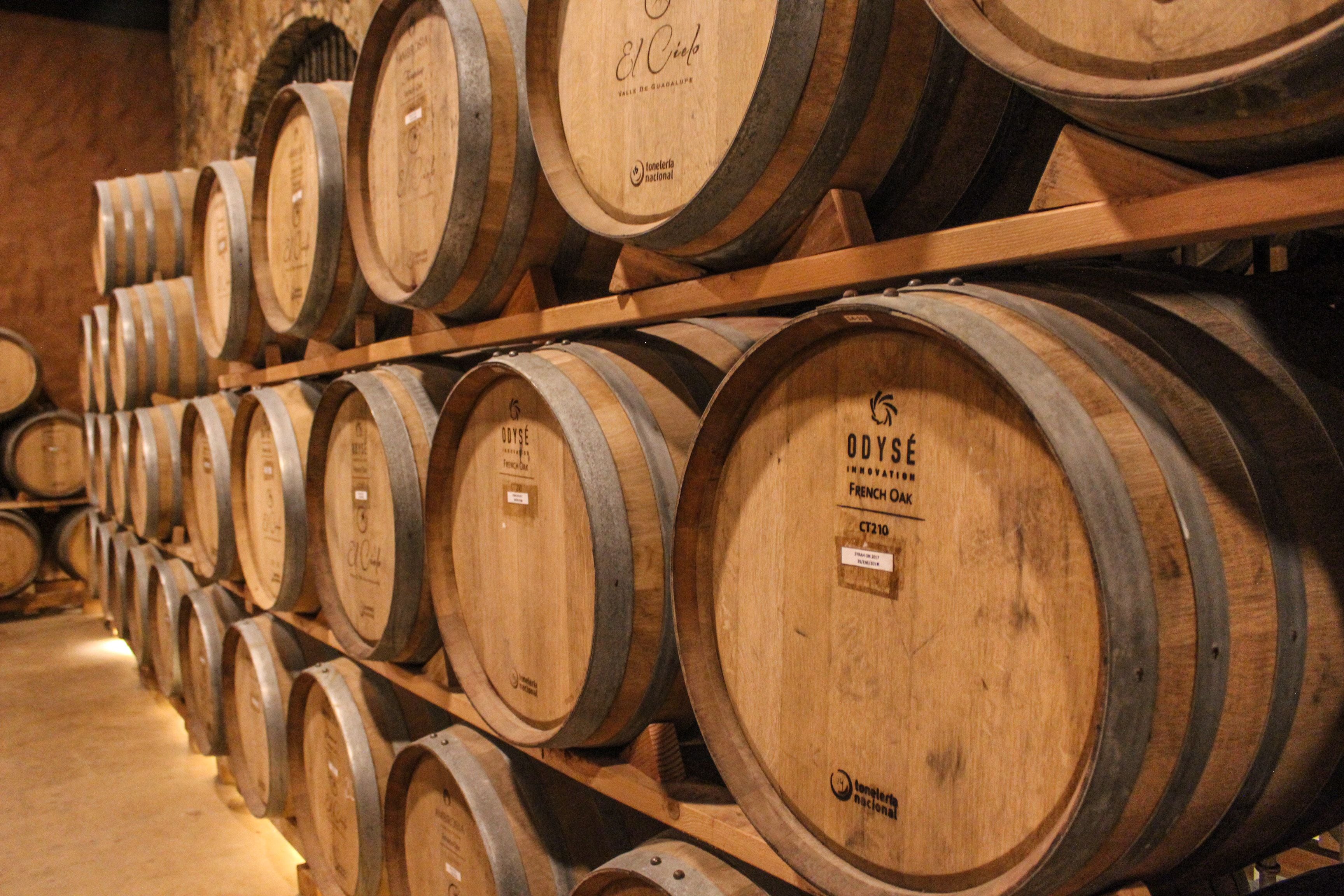 Wooden wine barrels stacked on shelves in a warehouse.