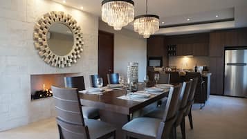 Un comedor moderno con un espejo redondo grande, chimenea y una araña.